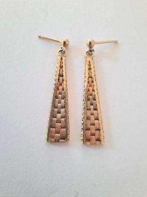 a pair of gold tone earrings on a white surface