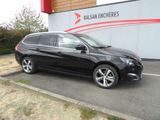 La voiture noire est garée devant un immeuble sur lequel est accrochée une pancarte.