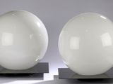 une paire de lampes en verre blanc posées sur des pieds en métal, sur un fond gris