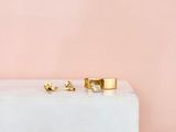 a pair of gold and diamond stud earrings sitting on top of a marble block