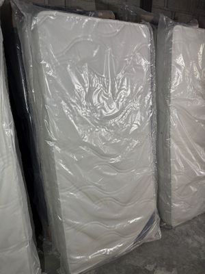 many mattresses that are wrapped in plastic in a warehouse
