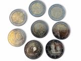 several different coins are arranged in a circle on a white surface
