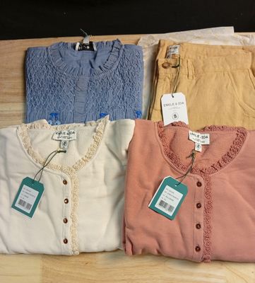 trois paires de chemises pour femmes, encore étiquetées, posées sur une table