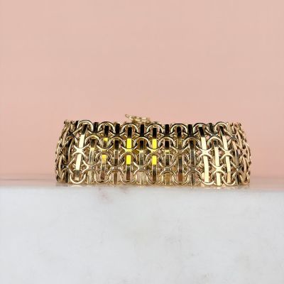 a close up of a gold bracelet on a marble surface