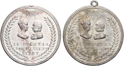 two silver medals with the names of two people on them