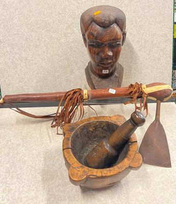 une statue en bois représentant un homme tenant un couteau et un mortier