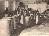 photographie en noir et blanc représentant des ouvriers dans une usine, avec de grands fûts