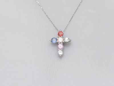 un collier avec une croix en or blanc sertie de pierres multicolores, monté sur une chaîne