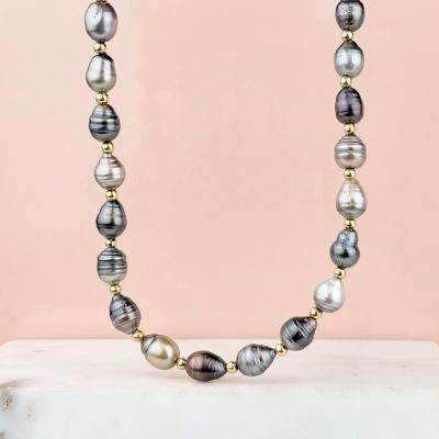 a necklace made of black and white pearls and gold beads