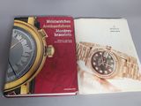 deux livres posés sur une table, avec une montre dessus, et une autre montre posée par-dessus