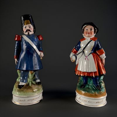 two figurines of men dressed in military uniforms are standing next to each other