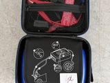 une valise noire sur laquelle est dessiné un voiture et une paire de chaussures orange