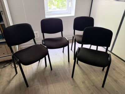 quatre chaises noires dans une pièce avec une fenêtre à l'arrière-plan