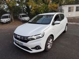 La voiture blanche est garée sur le parking à côté de la maison.