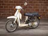 a white motor bike parked in front of a brick wall