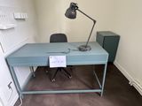 un bureau bleu sur lequel se trouve une lampe, dans une pièce