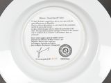 the plate is white with black writing on it and has a stamp on it