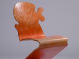 une chaise en bois dont l'assise est cassée, posée sur une surface blanche