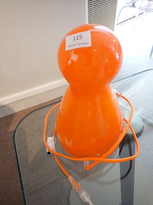 une lampe orange posée sur une table en verre