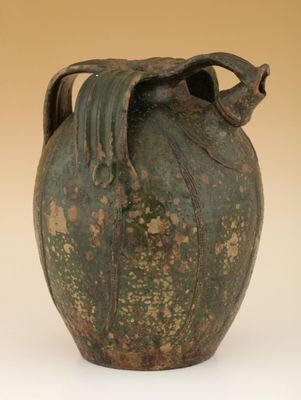 un grand vase vert avec un oiseau sur l'anse