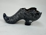 une chaussure noire posée sur une surface blanche