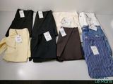 Plusieurs chemises et pantalons pour hommes sont alignés sur une table