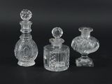 trois bouteilles en verre transparent et un petit vase en verre posés sur une surface noire
