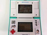 a white and green nintendo game console on a white surface