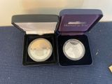 two silver and gold coins in a purple box on a blue carpet