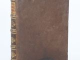 an old book with a brown cover sitting on top of a white surface