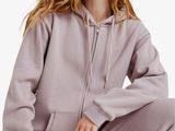 une femme vêtue d'un sweat à capuche violet et d'un pantalon de survêtement, accroupie
