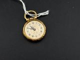 a small gold pocket watch with a chain on a black surface