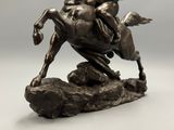statue of a man riding a horse on a rock on a gray background