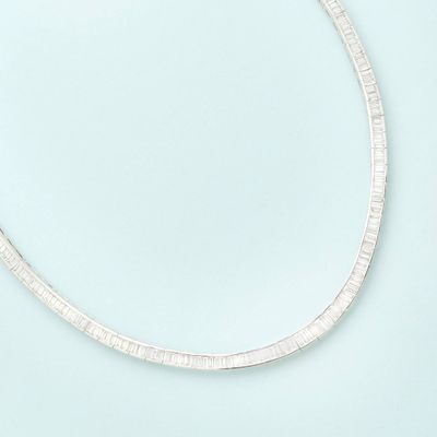 a close up of a silver necklace on a blue surface