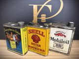 three tins of shell oil are sitting on a wooden table