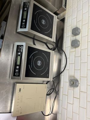 two microwaves sitting on top of a stove in a kitchen