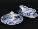 two blue and white dishes and a saucer on a black table