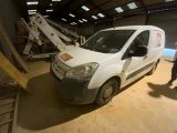 un homme debout à côté d'une camionnette blanche dans un garage