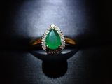 une bague sertie d'une émeraude et de diamants repose sur une surface noire