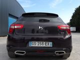 the rear end of a black car parked in front of a building
