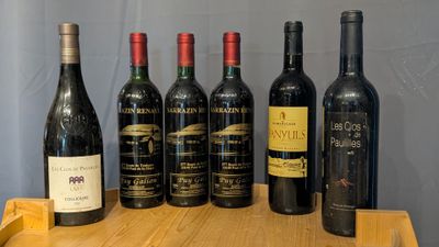 several bottles of wine are lined up on a wooden table