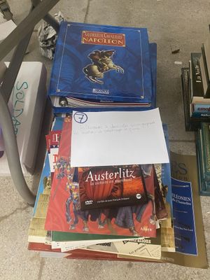 une pile de livres posée par terre à côté d'une chaise