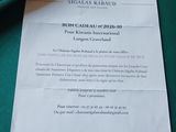 un bout de papier écrit au stylo posé sur une table, à côté d'une bouteille de vin