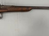 un fusil accroché au mur, à côté d'un mur blanc