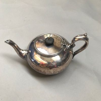 une théière en argent posée sur une nappe blanche