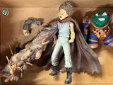 deux figurines dans une boîte : l'une représente un homme avec une cape et l'autre un monstre