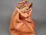 brown leather handbag sitting on a gray surface with a gray background