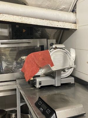 une photo d'une cuisine professionnelle avec un trancheur à viande posé sur le plan de travail