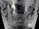 a glass vase with a deer and trees etched on it