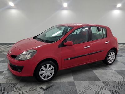 une voiture rouge est garée dans une pièce au sol en damier